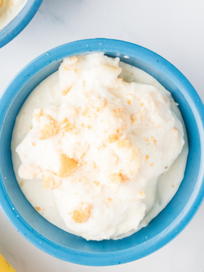 Two scoops of Ninja Creami Blue Bell banana pudding copycat ice cream in a white bowl with vanilla wafers
