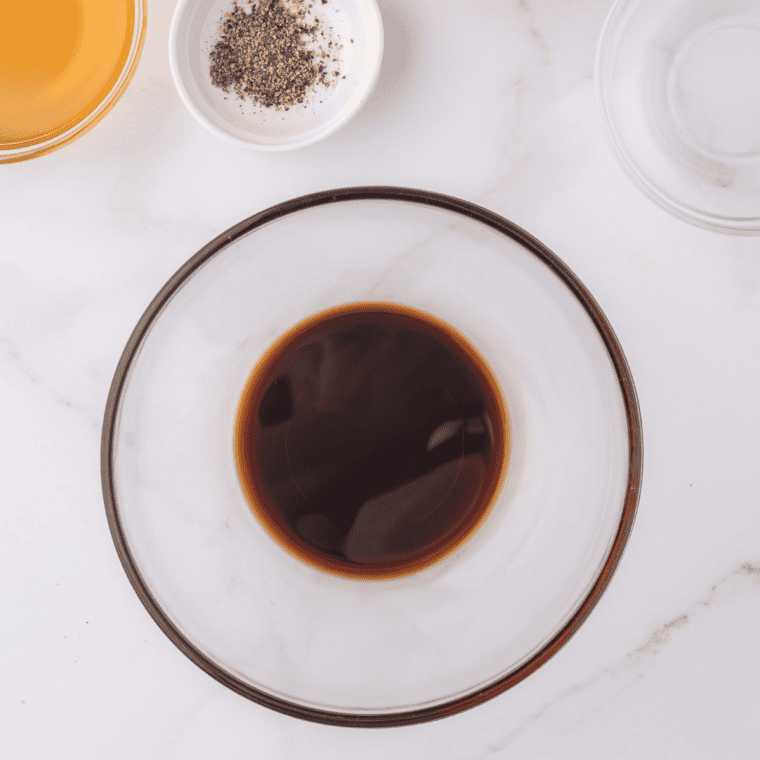 Whisking vinegar, brown sugar and molasses together in a glass bowl for hickory brown sugar marinade
