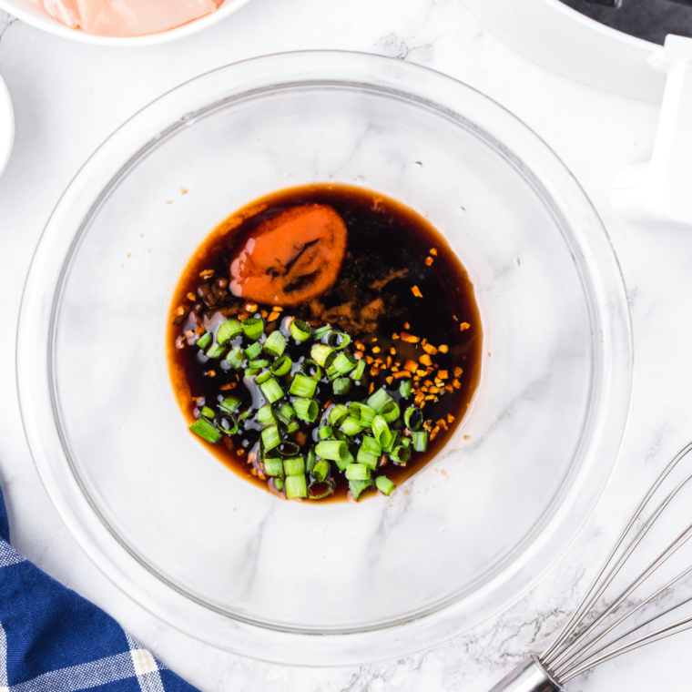 Whisking pineapple juice, soy sauce, and brown sugar together in a glass bowl to make homemade teriyaki marinade