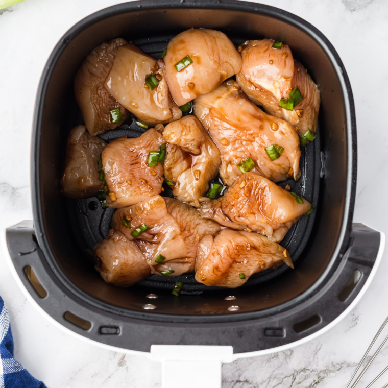 Teriyaki marinated chicken in an air fryer basket, brushed with copycat Lawry's pineapple marinade before cooking