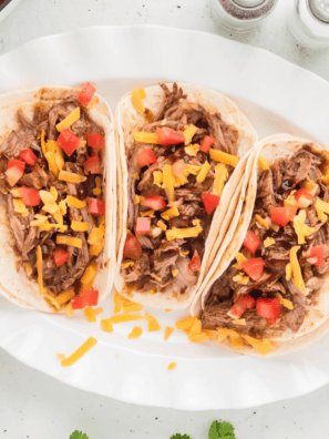 Plate of pork tacos seasoned with copycat McCormick al pastor seasoning, garnished with fresh lime and diced pineapple