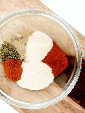 Cornstarch, paprika, thyme, onion powder and other spices in a white bowl before mixing into beef stew seasoning