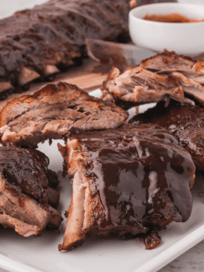 Baby back ribs glazed with homemade Copycat Stubb's Dr Pepper Barbecue Sauce, sliced and sticky on a wooden board