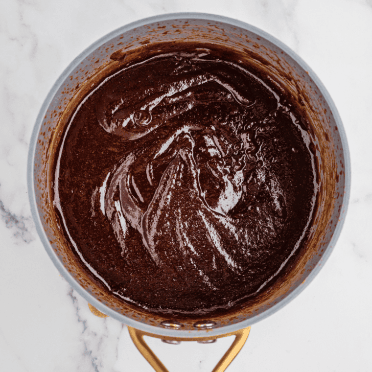 Copycat Stubb's Dr Pepper Barbecue Sauce simmering on low and thickening until glossy in a saucepan