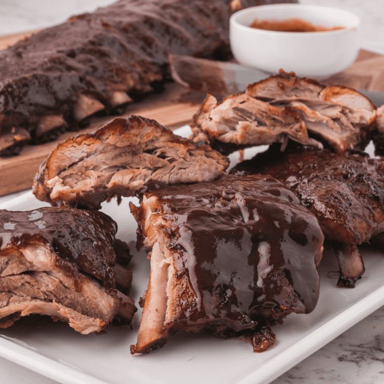 Baby back ribs glazed with homemade Copycat Stubb's Dr Pepper Barbecue Sauce, sliced and sticky on a wooden board