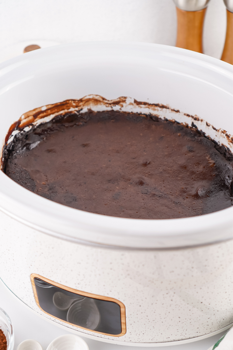 Chocolate cobbler in crockpot with a spoon lifting tender cake and hot fudge sauce