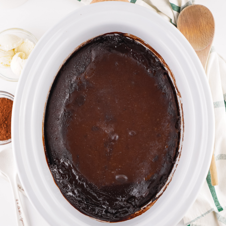 Overhead view of crock pot chocolate cobbler in a slow cooker with a crackly cake top and fudge sauce showing through