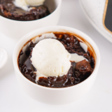 Chocolate cobbler in crockpot with a spoon lifting tender cake and hot fudge sauce