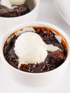 Chocolate cobbler in crockpot with a spoon lifting tender cake and hot fudge sauce