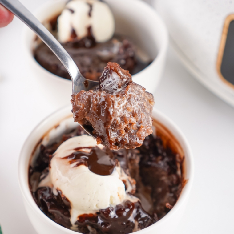 Crock pot chocolate cobbler in a white slow cooker, tender chocolate cake broken open to show hot fudge sauce underneath