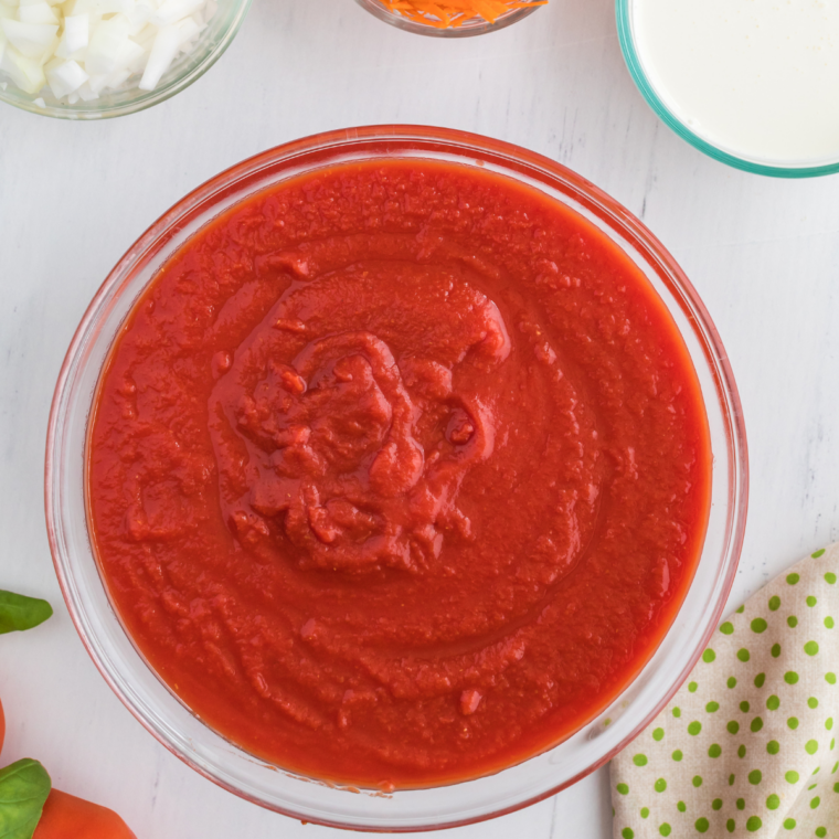Ingredients to make canned tomato soup taste homemade: a can of condensed soup, butter, garlic, milk, cream, Parmesan, and basil.