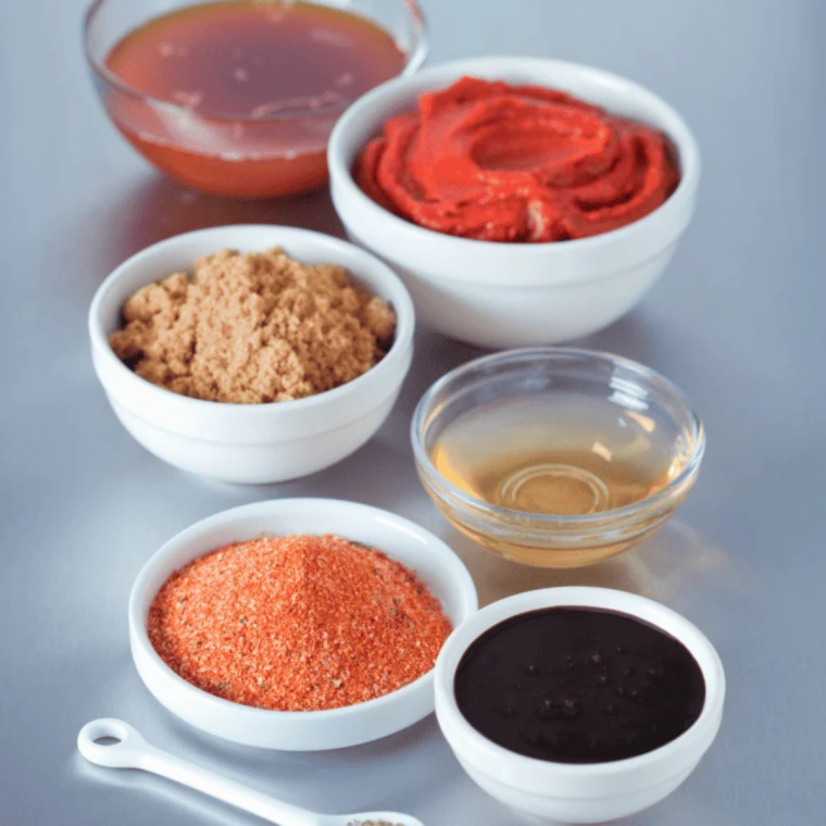 Ingredients for copycat Ken's Boom Boom Sauce on a wooden table: mayonnaise, hot sauce, Dijon, roasted red pepper, and shallot