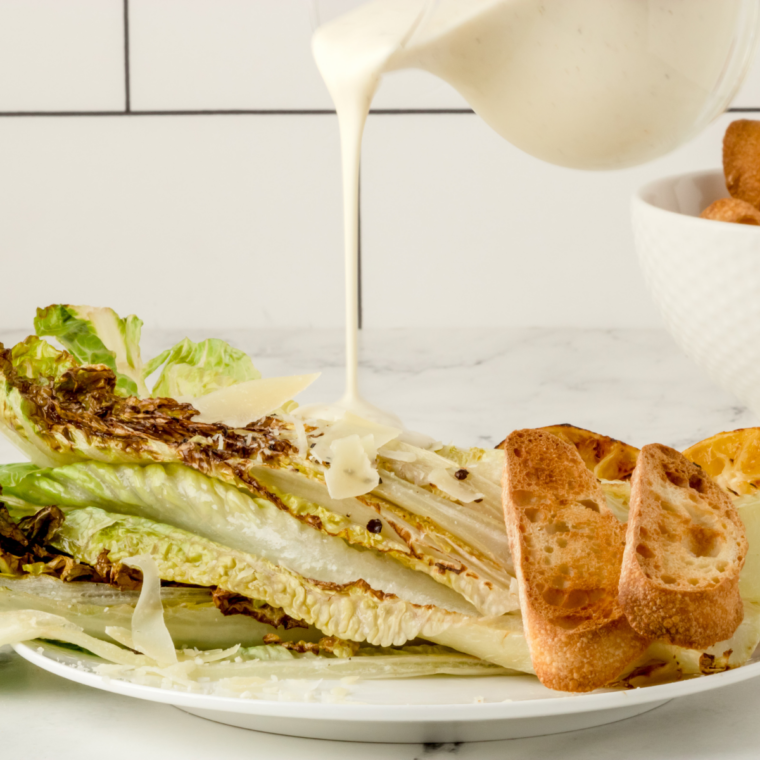 Creamy copycat LongHorn Caesar dressing being drizzled over romaine
