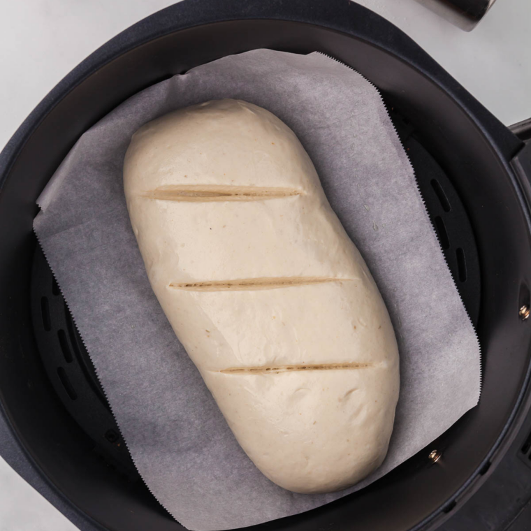 Round boule of Longhorn Steakhouse honey wheat bread baking in an air fryer basket