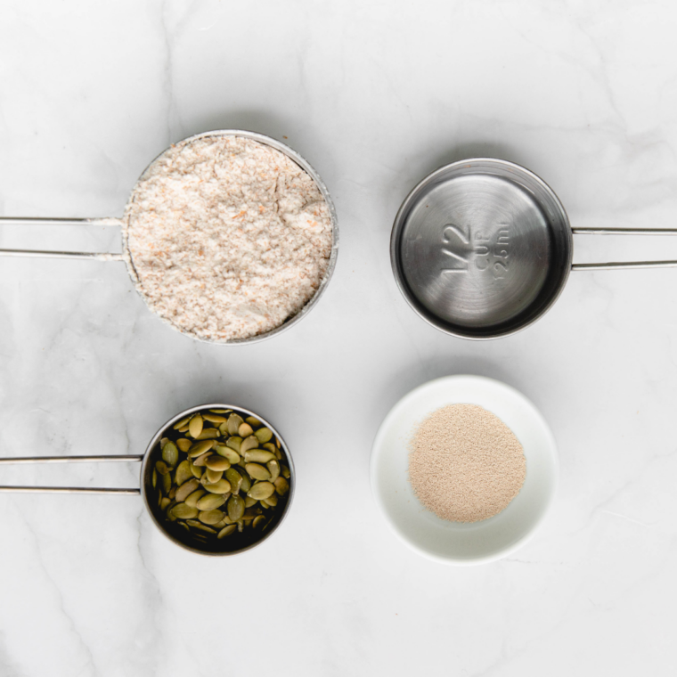 Ingredients for Longhorn Steakhouse bread — whole wheat flour, honey, buttermilk, yeast, butter, and mixed grains in bowls