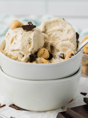 Ninja Creami chocolate chip cookie dough blizzard in a glass bowl topped with cookie dough chunks and chocolate chips