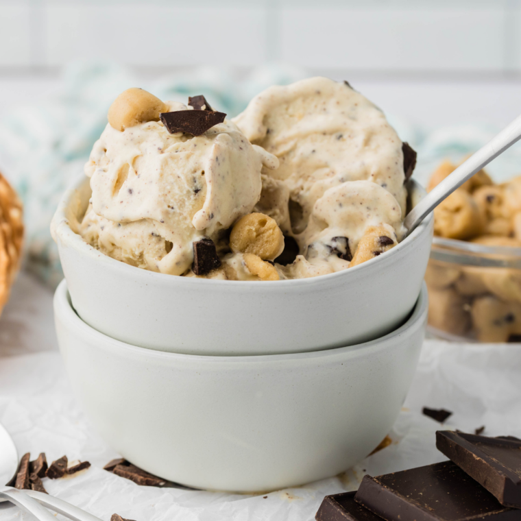 Ninja Creami chocolate chip cookie dough blizzard in a glass bowl topped with cookie dough chunks and chocolate chips