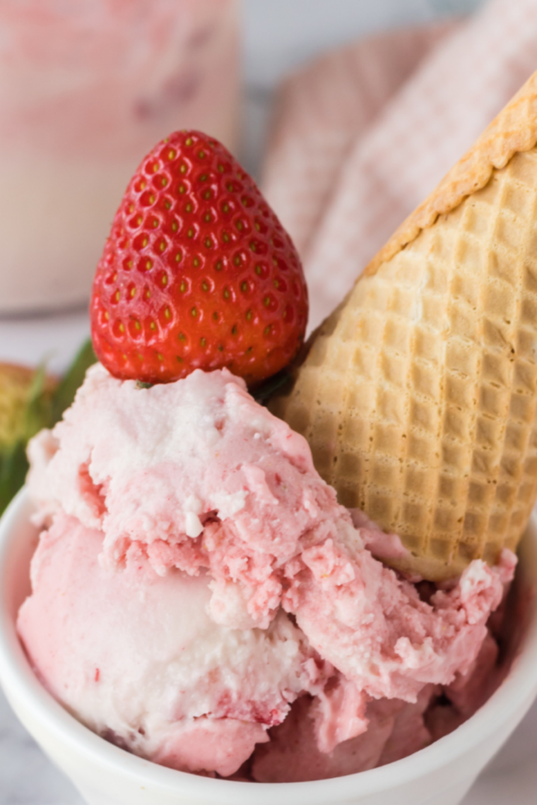Ninja Creami copycat Blue Bell Strawberry ice cream in a white bowl with real strawberry pieces throughout