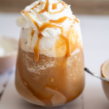 Ninja Creami frappe in a tall glass topped with whipped cream and a straw