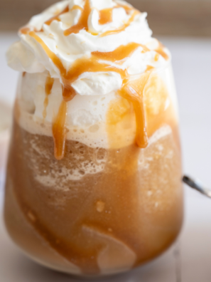 Ninja Creami frappe in a tall glass topped with whipped cream and a straw