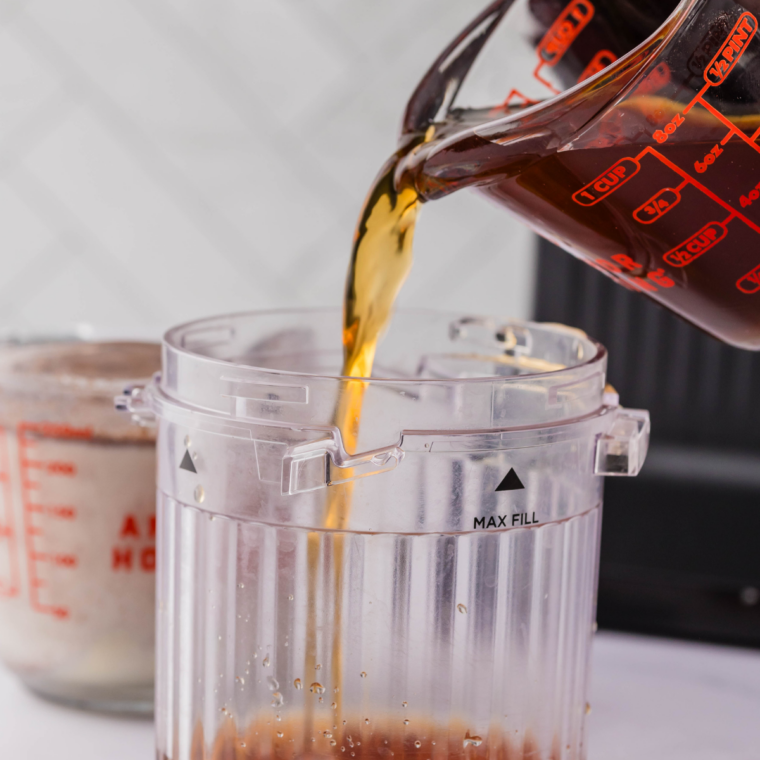 Pouring chilled brewed coffee into a Ninja Creami pint container