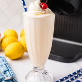 Ninja Creami Frosted Lemonade copycat milkshake in a tall glass topped with whipped cream and a lemon slice