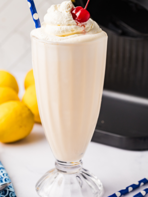Ninja Creami Frosted Lemonade copycat milkshake in a tall glass topped with whipped cream and a lemon slice