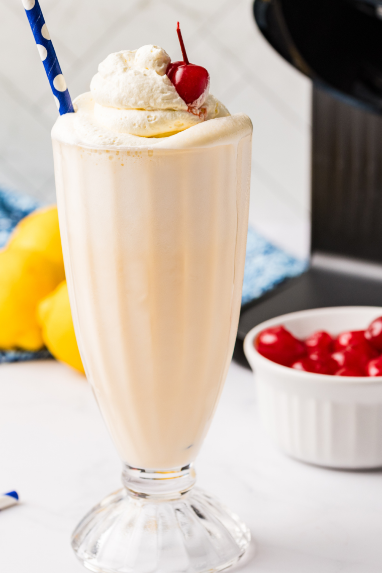 Creamy Ninja Creami Frosted Lemonade milkshake garnished with fresh lemon zest and a striped straw