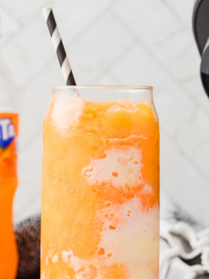 Ninja Creami Fanta Float Slushie in a tall glass topped with a scoop of vanilla ice cream, straw, and spoon