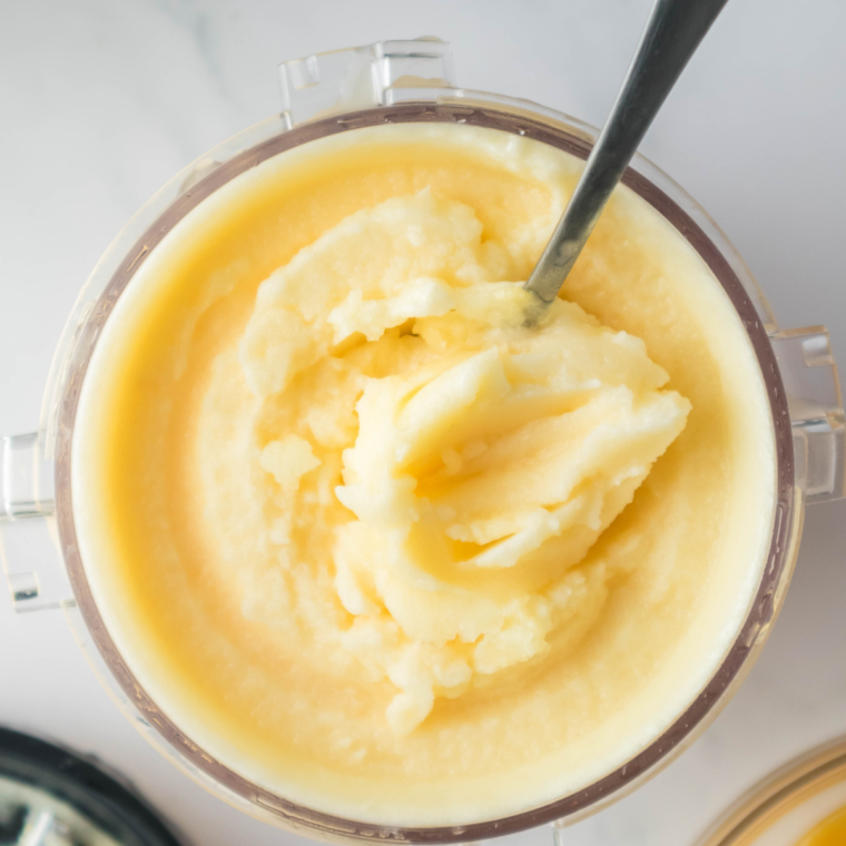 Ninja Creami Lemon Italian Ice scooped into a white bowl, garnished with a fresh lemon slice and mint