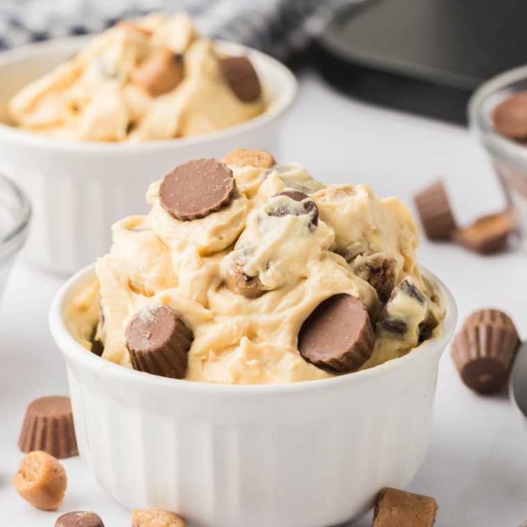 Two scoops of creamy Ninja Creami peanut butter ice cream served in a white dish, topped with crushed peanuts.