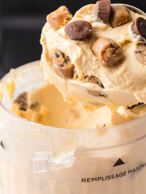 Two scoops of creamy Ninja Creami peanut butter ice cream in a white bowl, topped with crushed peanuts.