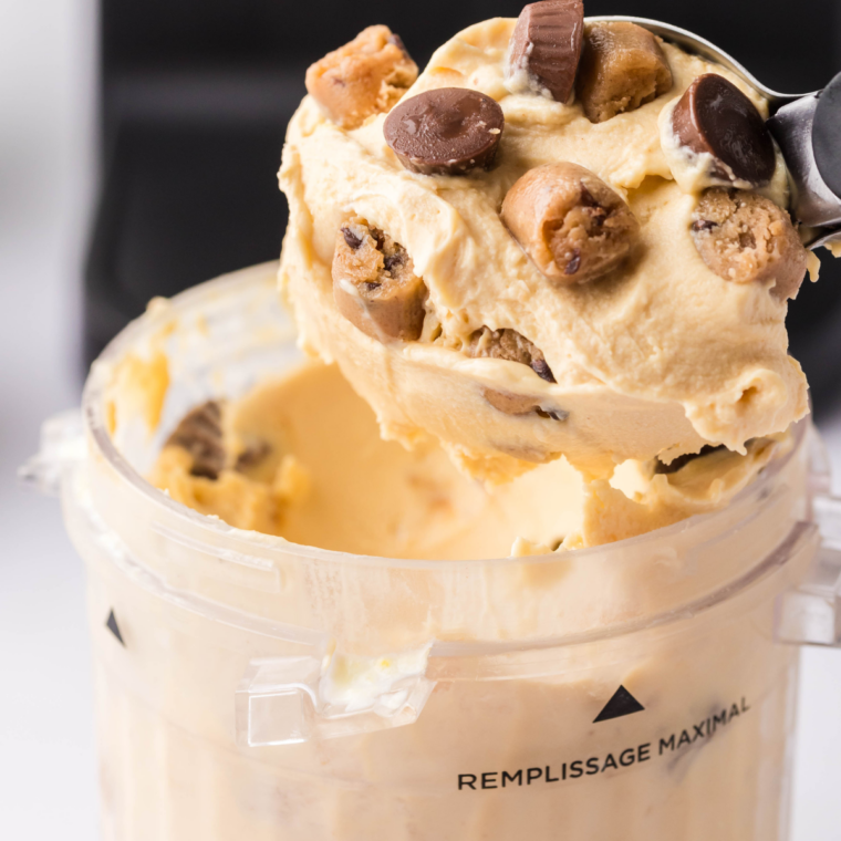 Two scoops of creamy Ninja Creami peanut butter ice cream in a white bowl, topped with crushed peanuts.