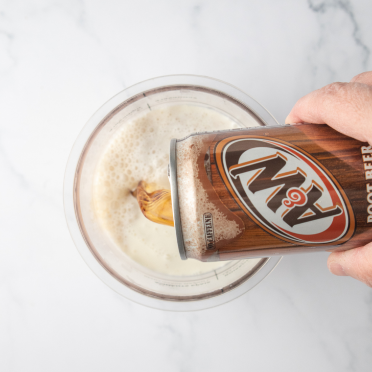 Whisking root beer, sugar, heavy cream, and vanilla together in a measuring cup to make the base