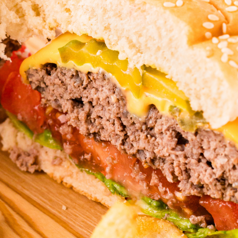 Cheeseburger cut in half showing a juicy interior and browned crust from the Ninja Crispi