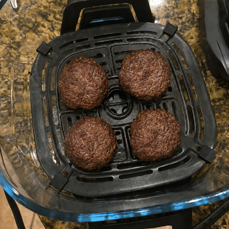 Cheeseburger patties with melted American cheese in the Ninja Crispi glass container