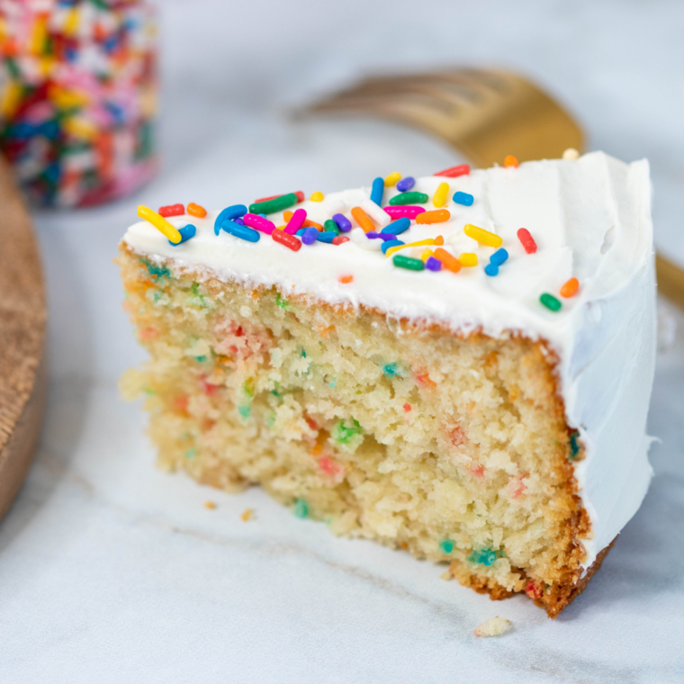 Round vanilla cake frosted in white buttercream and topped with sprinkles