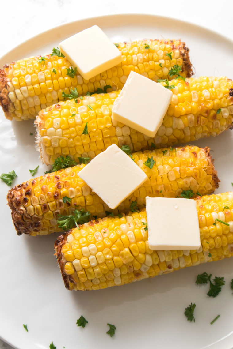Charred corn kernels being cut from the cob into a bowl with a knife
