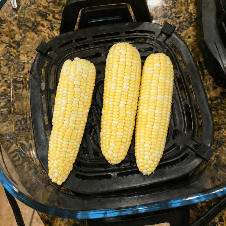 Four corn halves arranged in a single layer on the crisper plate in the Ninja Crispi container
