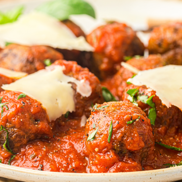 Ninja Crispi meatballs with browned, craggy crusts resting on the crisper plate inside the glass container