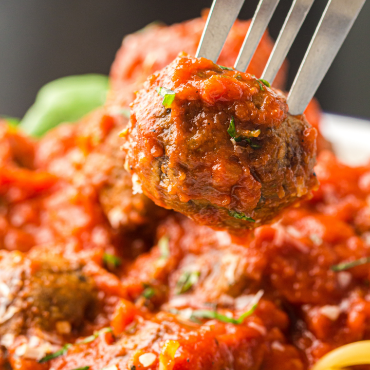 Ninja Crispi meatballs with deep brown crusts resting in the glass container after cooking