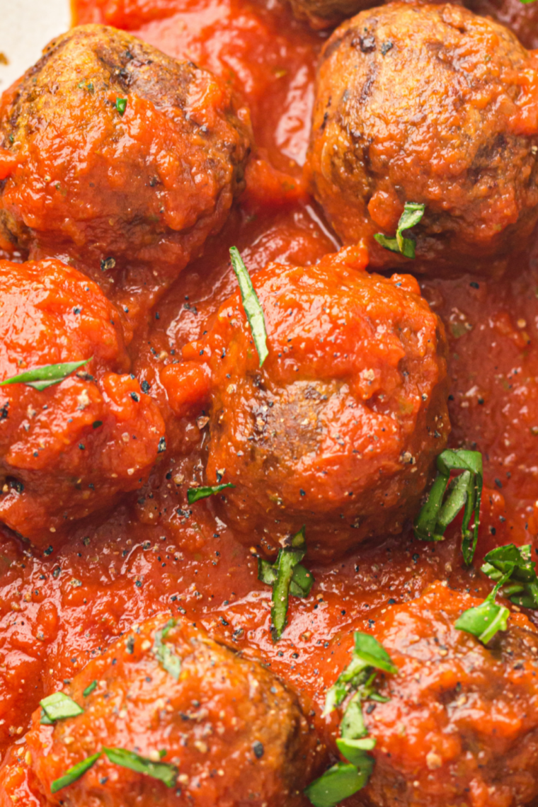 Air fried meatballs on a platter with toothpicks and a bowl of warm marinara for dipping