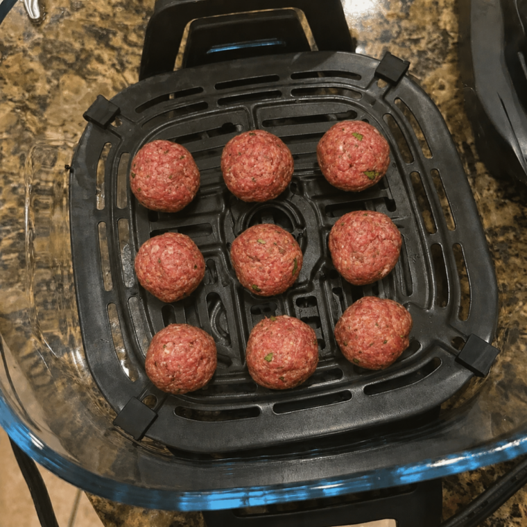 Raw meatballs arranged in a single layer on the crisper plate in the 4-quart Ninja Crispi glass container