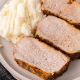 Sliced Ninja Crispi pork tenderloin with a golden crust served over mashed potatoes on a white plate