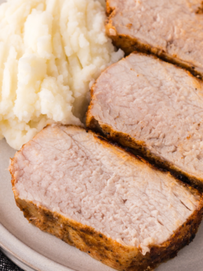 Sliced Ninja Crispi pork tenderloin with a golden crust served over mashed potatoes on a white plate