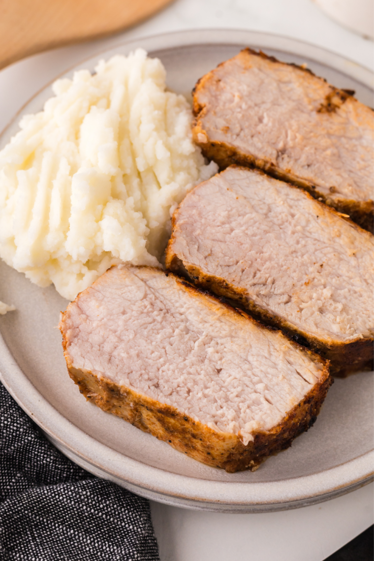 Resting Ninja Crispi pork tenderloin sliced into medallions against the grain