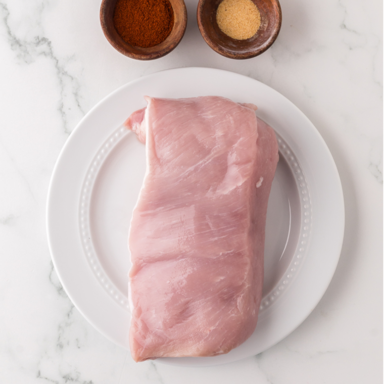 Ninja Crispi pork tenderloin ingredients: raw tenderloin, olive oil, and seasonings laid out on a counter