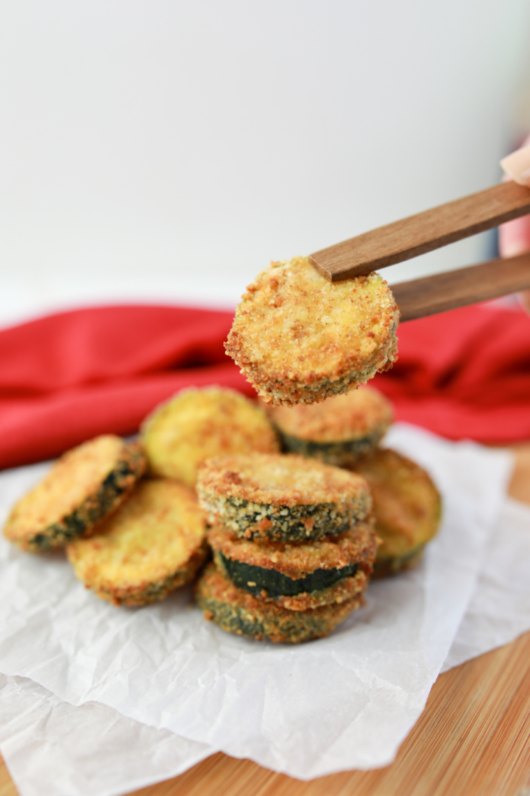 Sliced zucchini rounds being pressed into parmesan and panko breading