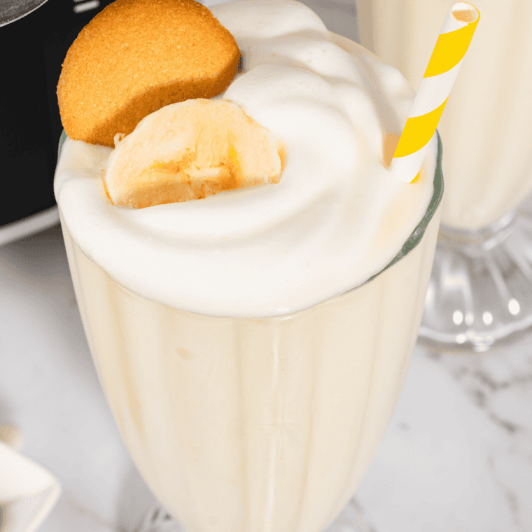 Tall glass of frozen Ninja Slushi banana milkshake with a striped straw