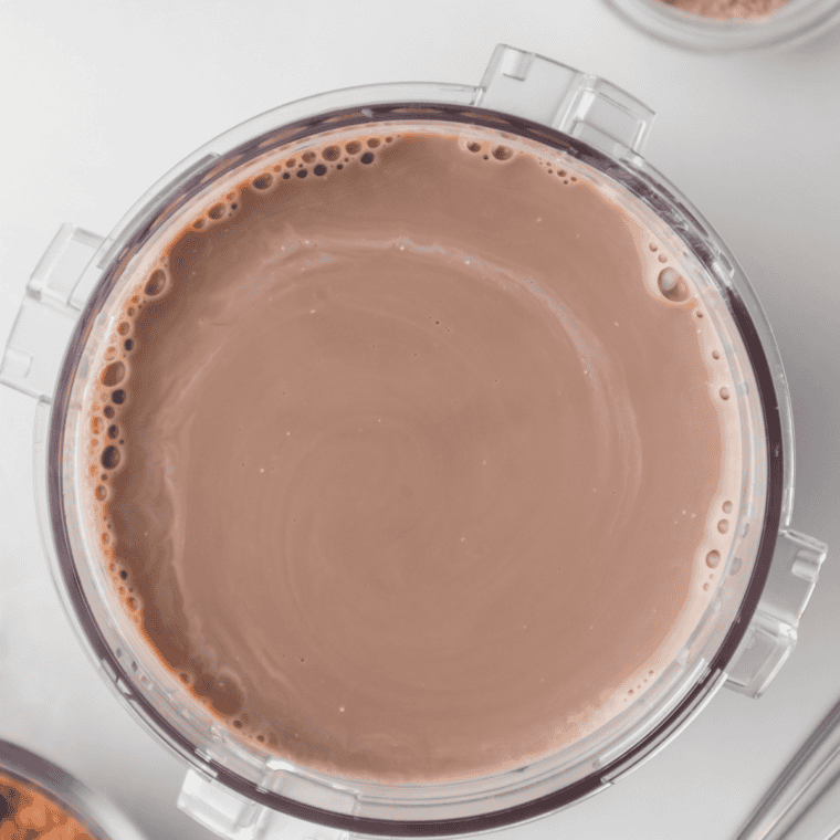 Whisking milk, chocolate pudding mix, sugar, and vanilla together in a bowl for a Ninja Slushi milkshake